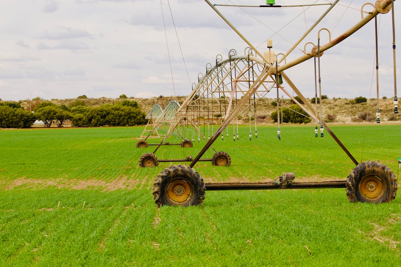 hero-about An advanced irrigation system waters a lush green field under a cloudy sky, enhancing farming efficiency.
