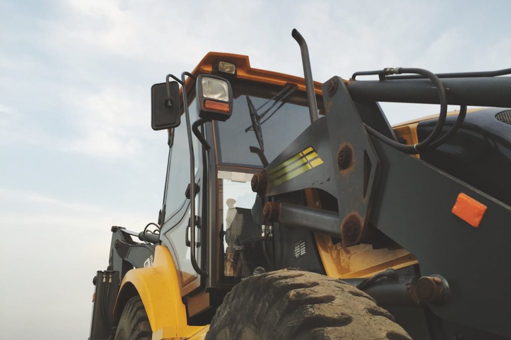 yellow-and-black-heavy-equipment-under-blue-sky-14651 Detailed view of a yellow excavator against a clear sky at a construction site.